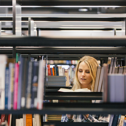 Une étudiante feuilletant un livre dans les couloirs de la librairie